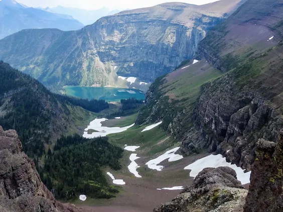Scenic image of Akamina Pass in Waterton National Park from above on a high elevation overlooking a hiking trail towards a glacier lake and Rocky Mountain cliffsides