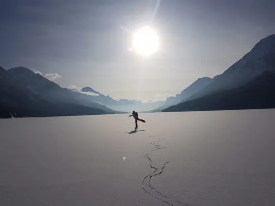 Image of a person skating on Waterton National Park with the lake valley in the background.