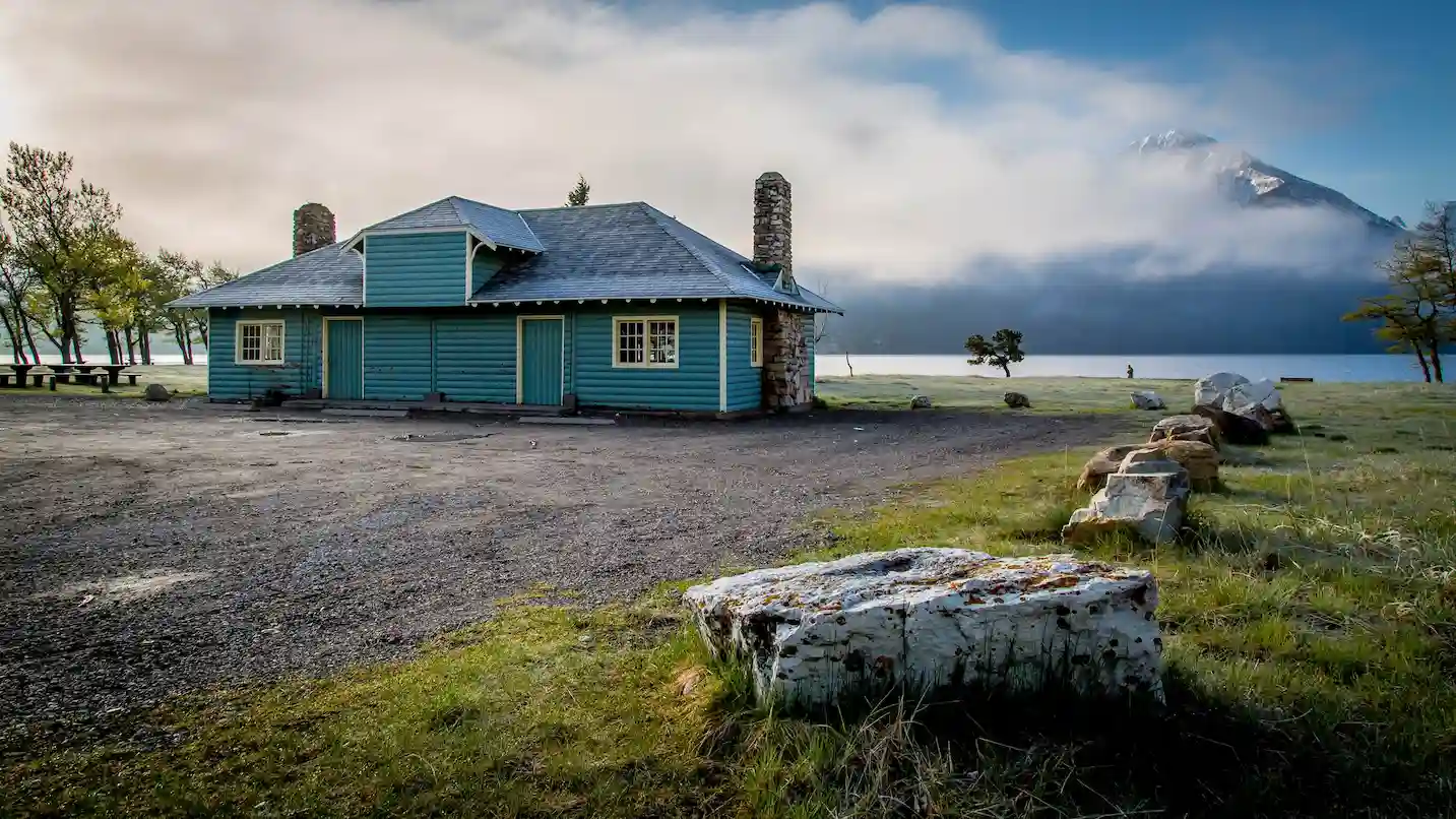 Image of a kitchen shelter in Waterton National Park with a lake visible behind in the background with a mountain peeking through the clouds.